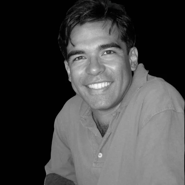 Smiling man portrait in black and white, close-up headshot against dark background