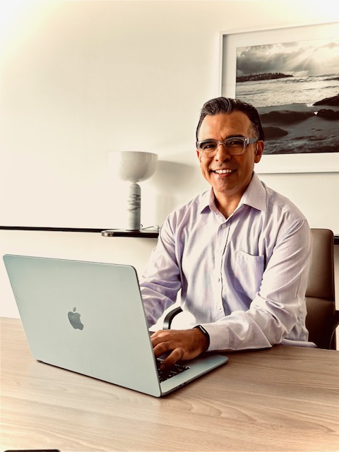 Francisco Romero, qualified counsellor and psychotherapist at Fostering Change Counselling, seated at a laptop.