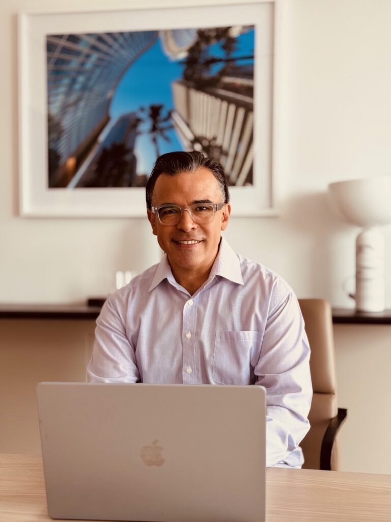Francisco Romero, qualified counsellor and psychotherapist at Fostering Change Counselling, seated at a laptop.