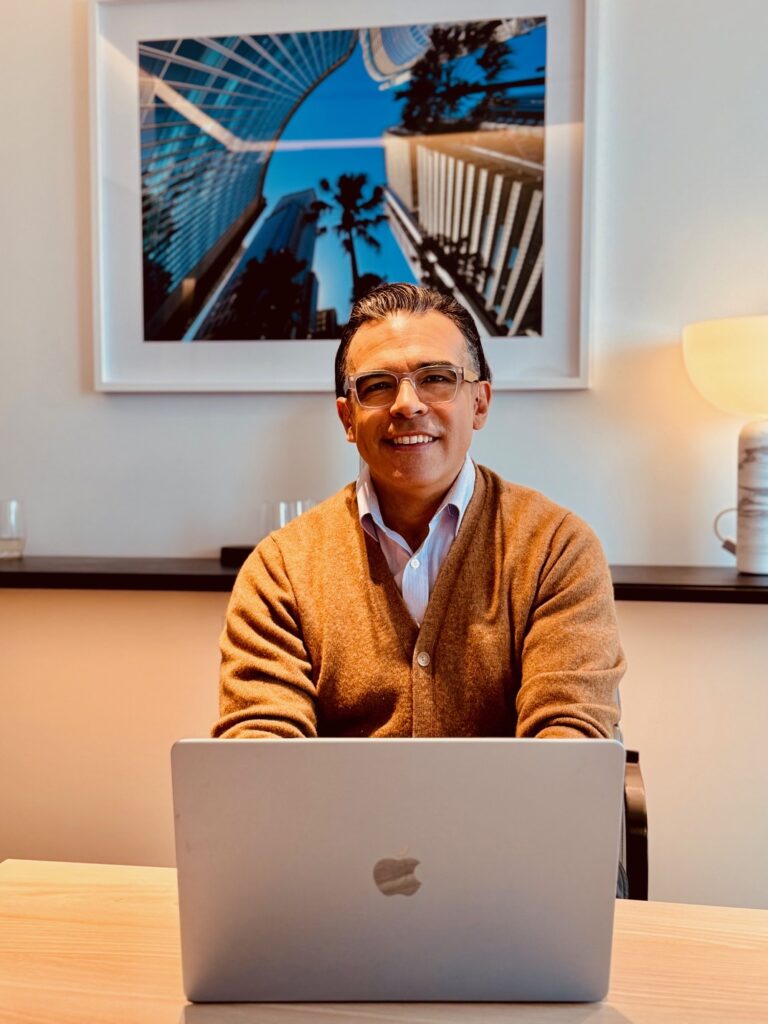 Francisco Romero, qualified counsellor and psychotherapist at Fostering Change Counselling, seated at a laptop.